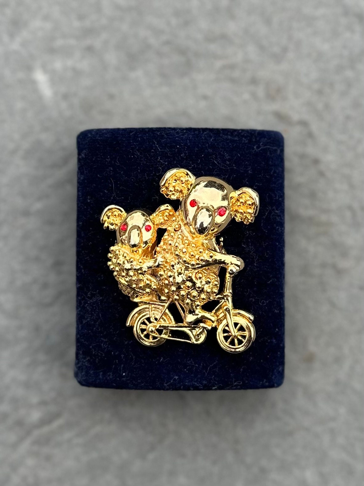 Vintage Gold Tone Koala Bear and Cub with Red Rhinestone Eyes Riding a Bike Brooch Pin