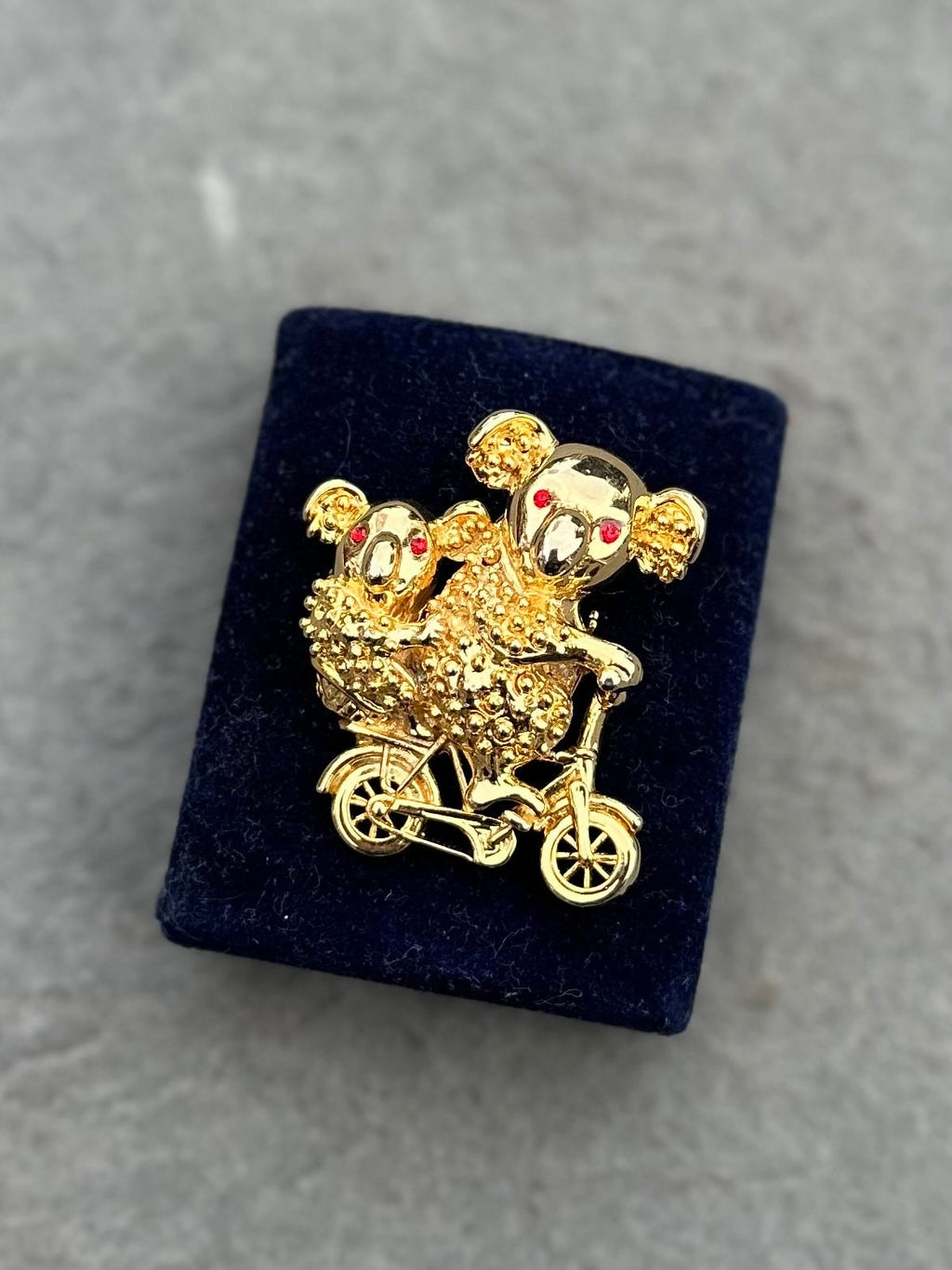 Vintage Gold Tone Koala Bear and Cub with Red Rhinestone Eyes Riding a Bike Brooch Pin