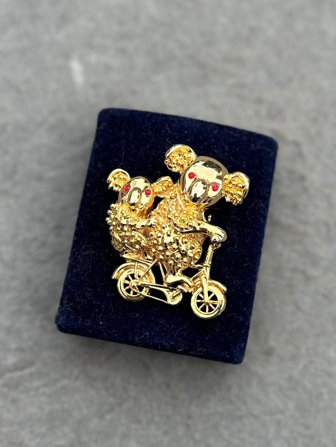 Vintage Gold Tone Koala Bear and Cub with Red Rhinestone Eyes Riding a Bike Brooch Pin